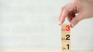 A set of wooden blocks showing levels 1, 2, and 3 being stacked by a hand, representing the range of autism levels.