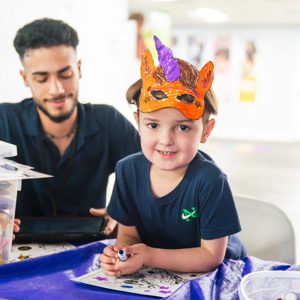 ABA therapist supporting a child during an autism-friendly craft activity.