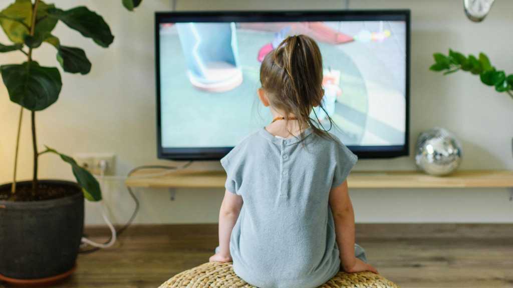 Young girl watching animated TV, representing characters with autism in pop culture.