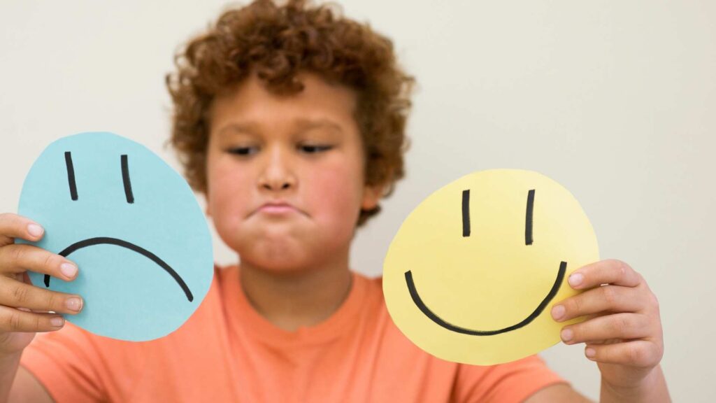 Child comparing happy and sad signs during an emotion‑identification activity