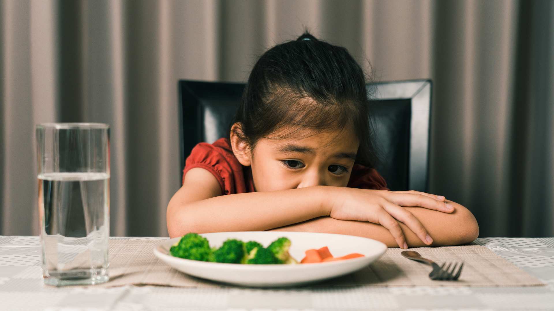 Child leaning on the table with food left on the plate to show challenges with eating in autism