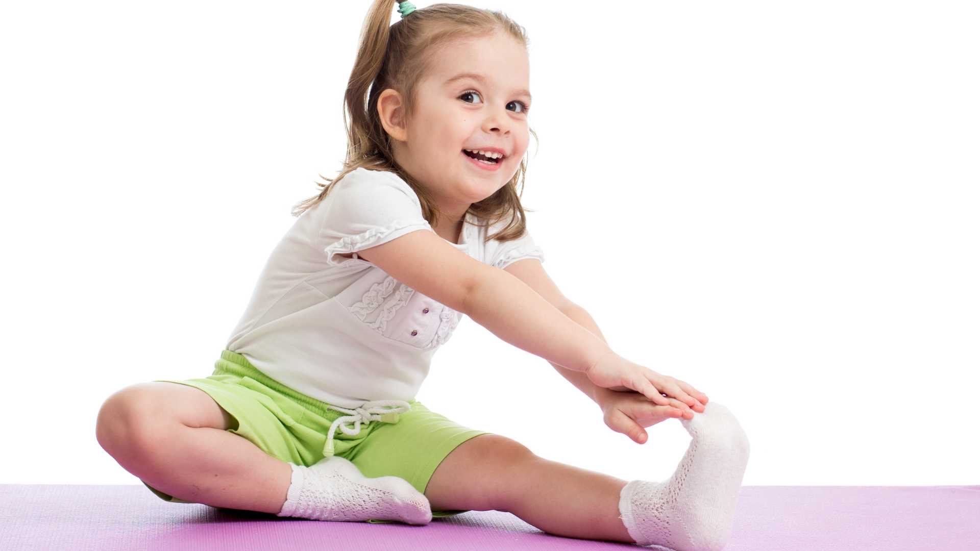 Sensory fit gym: A smiling girl is stretching, reaching for her toes on the floor.