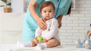 A pediatrician using a stethoscope to examine an 18-month-old during a checkup, demonstrating how to talk to your pediatrician about autism concerns during routine appointments