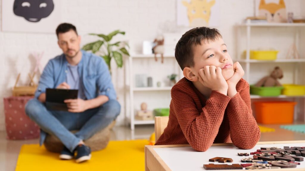 Behavior specialist observing a boy staring off rather than playing
