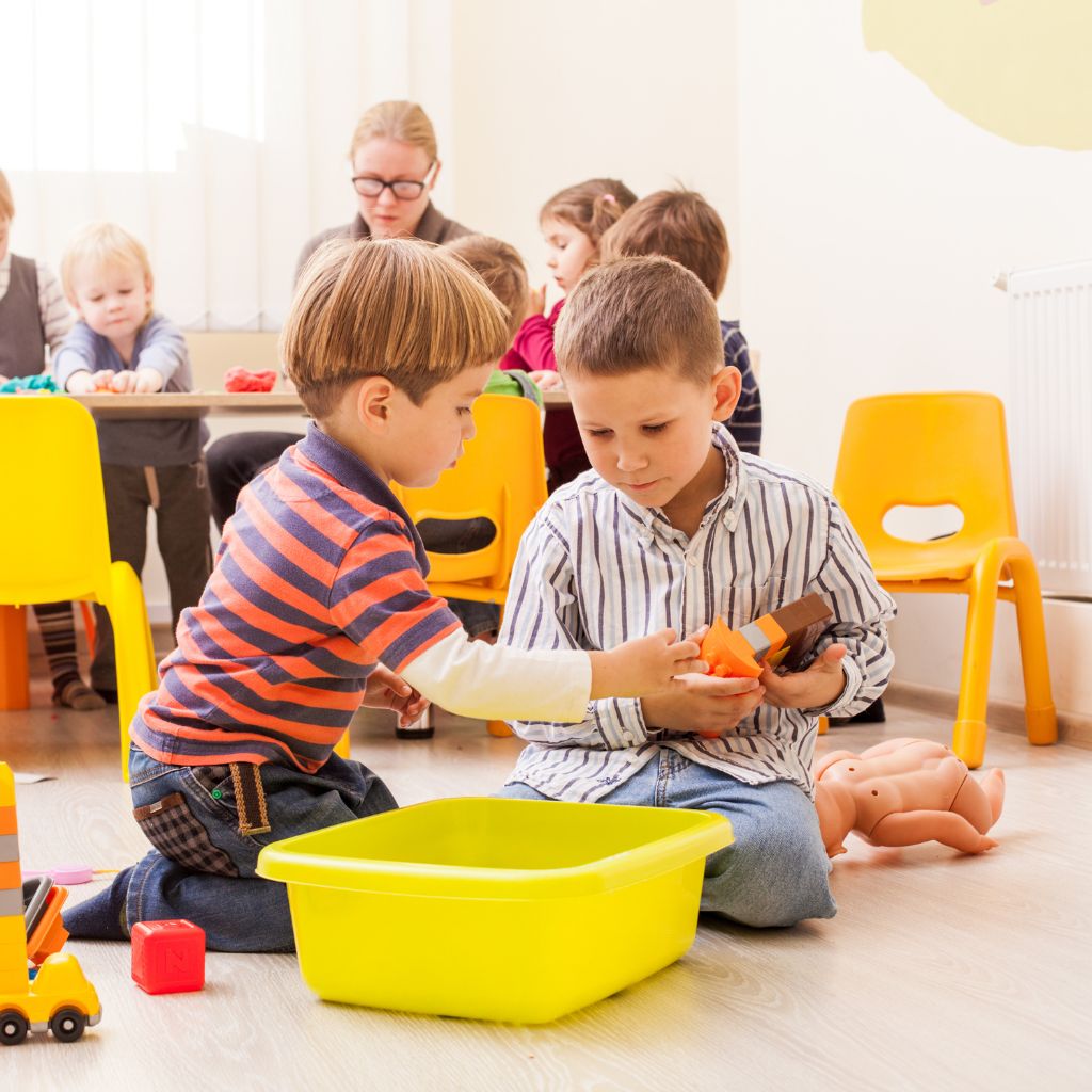 Two children building social interaction skills through cooperative play in a preschool setting.