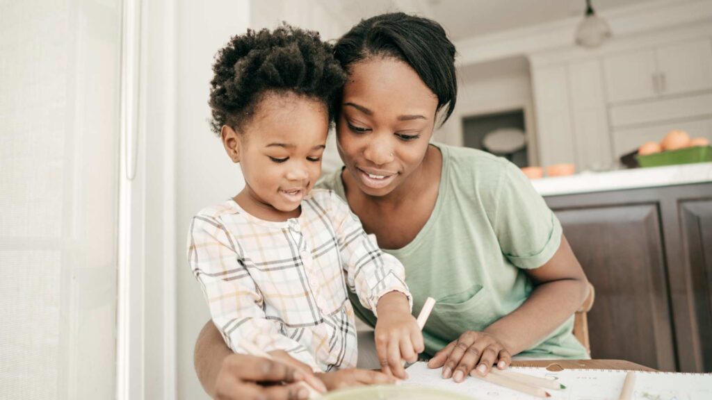 Parent helping young child practice learning skills during a home-based activity