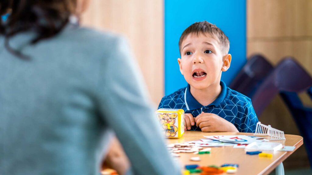 Child practicing communication skills with a therapist during an ABA communication skills therapy session