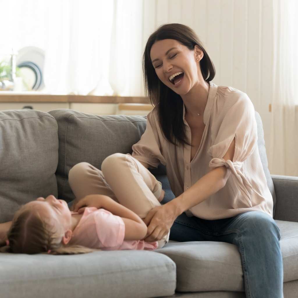 Mother laughing and sharing a joyful moment with her young daughter after autism acceptance