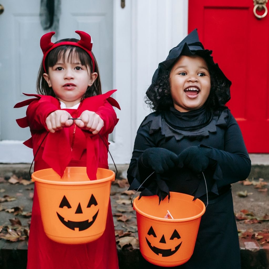 Children in Halloween costumes holding trick-or-treat buckets