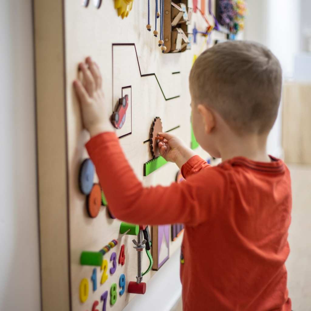 Young child engaging with a sensory activity board during ABA early intervention