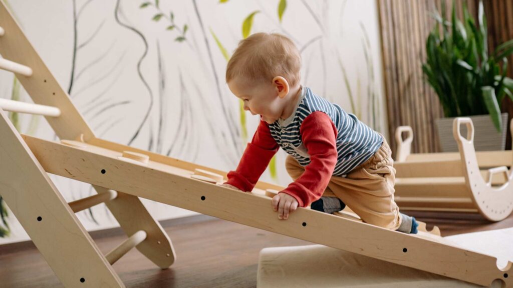 Toddler climbing on indoor play equipment during an early intervention activity in ABA therapy for toddlers