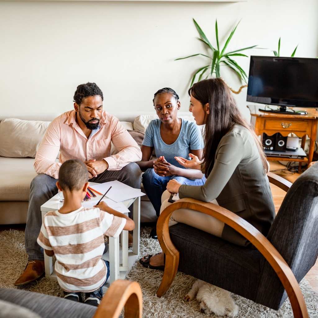 Parents meeting with an ABA professional while a child participates in an activity