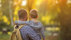 Father carrying his young child outdoors after facing grief in autism