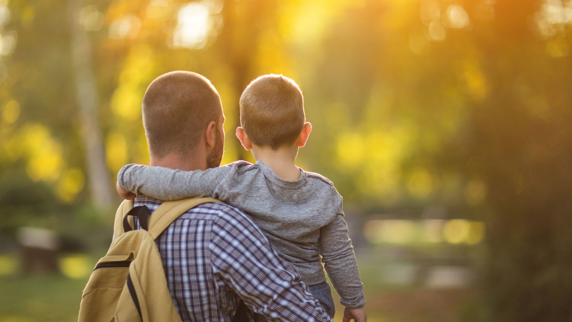 Father carrying his young child outdoors after facing grief in autism