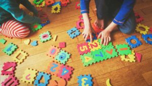 Children playing with colorful educational puzzle pieces in a play-based ABA therapy session