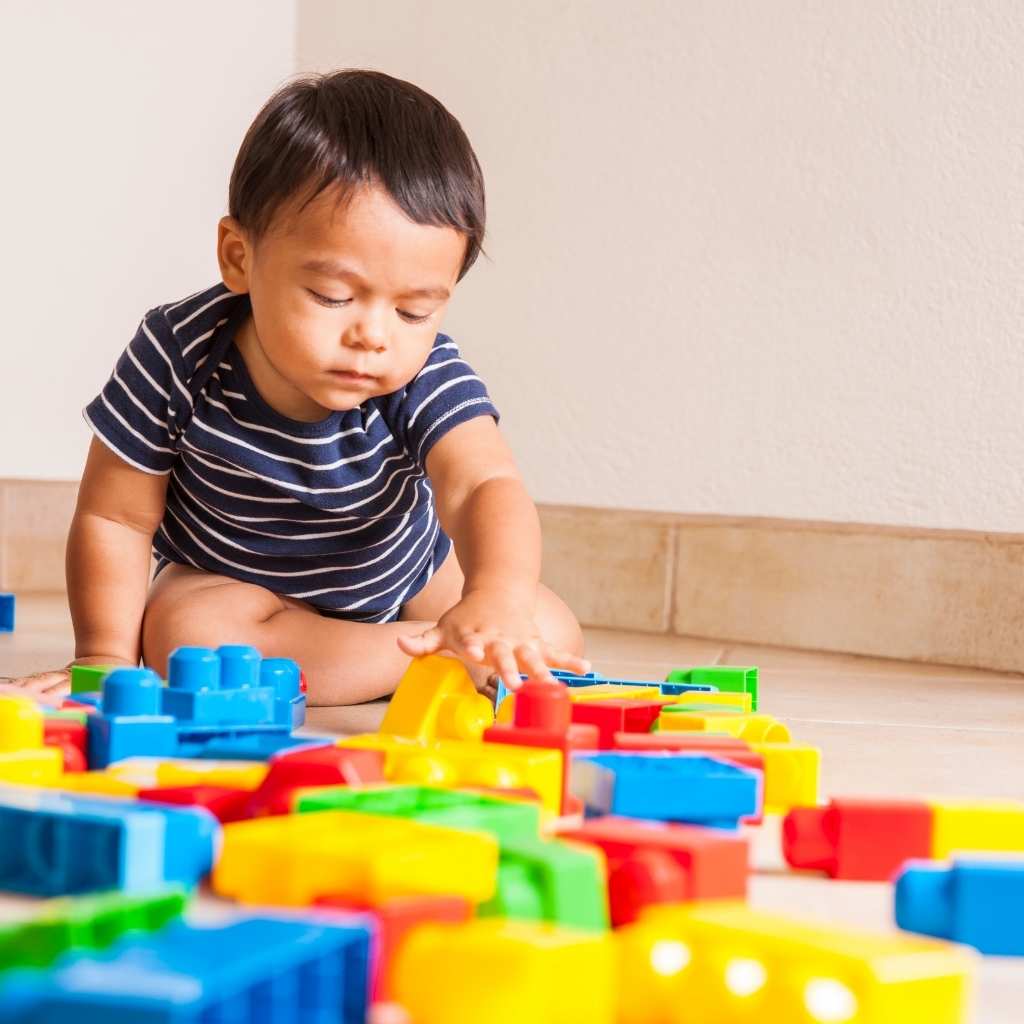 Toddler exploring colorful building blocks during a play-based aba learning activity