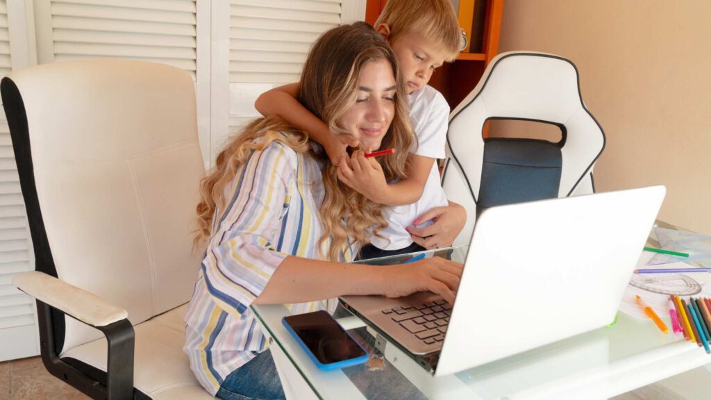 Parent helping a child while researching autism resources on a laptop at home