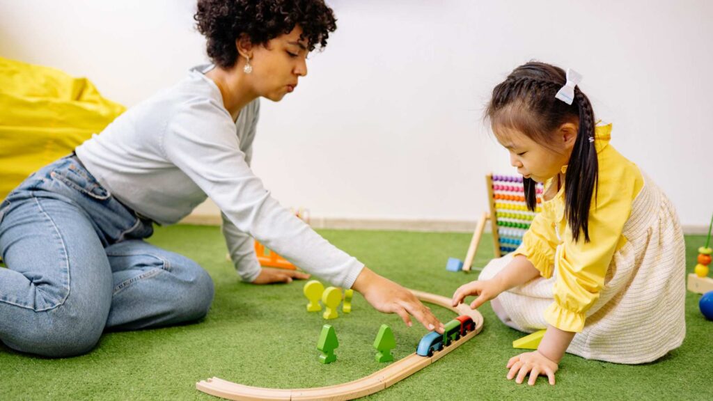 Therapist and child playing with a toy train during a play-based ABA therapy session