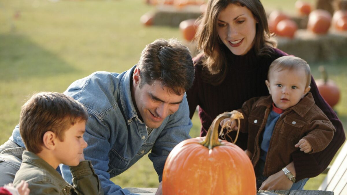 Family enjoying a Halloween pumpkin activity together outdoors