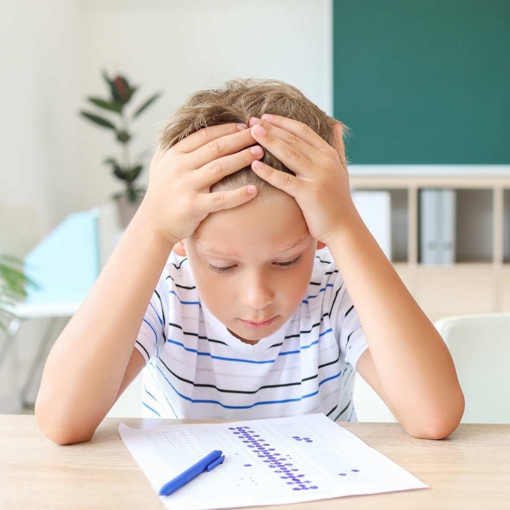 Child feeling overwhelmed while completing schoolwork at a desk