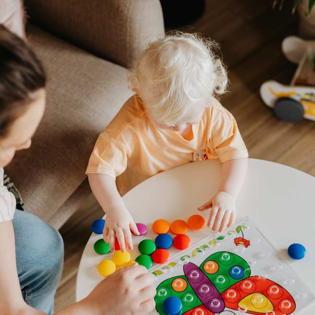 Toddler playing with colorful toys during autism screening for toddlers