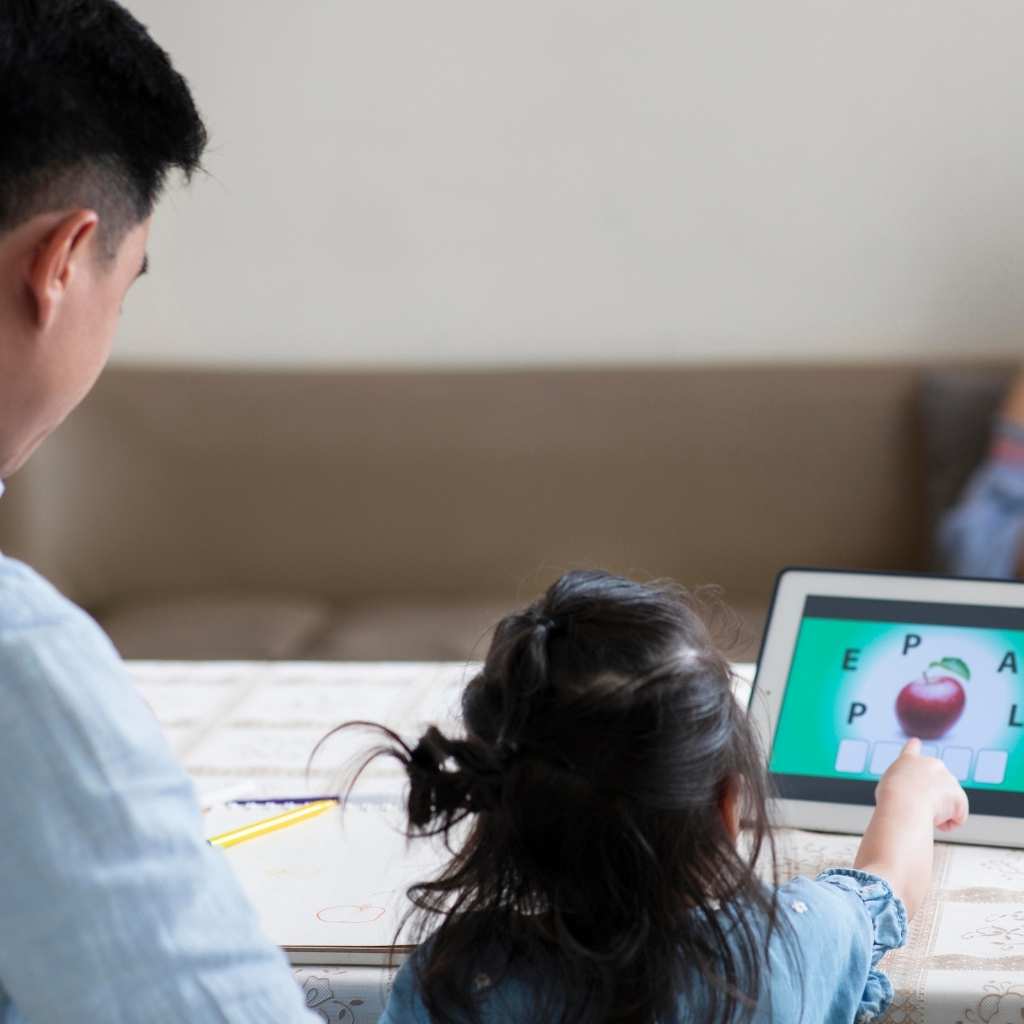 Child using a tablet-based visual communication activity with caregiver support to develop ABA communication skills